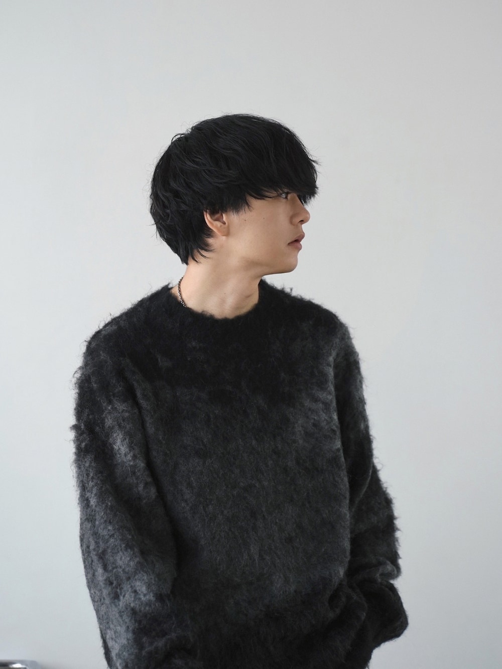 グレー系のチェスターコート、グレー系のニット/セーター、ブラック系のその他パンツを着用したメンズの冬コーディネートの4枚目の写真