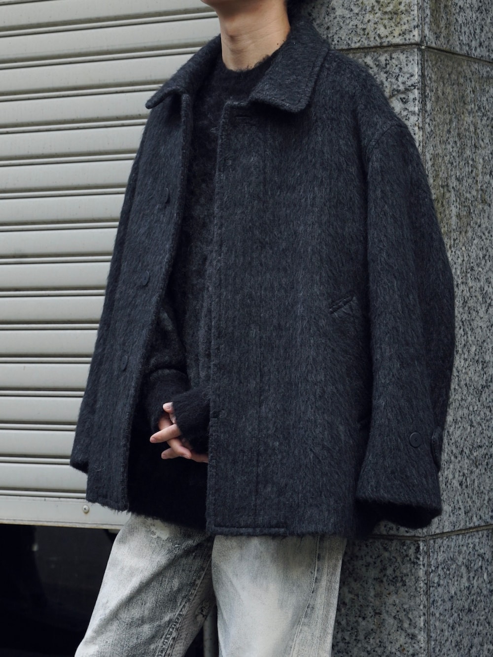 グレー系のブルゾン、グレー系のニット/セーター、ブラック系のデニムパンツを着用したメンズの冬コーディネートの4枚目の写真