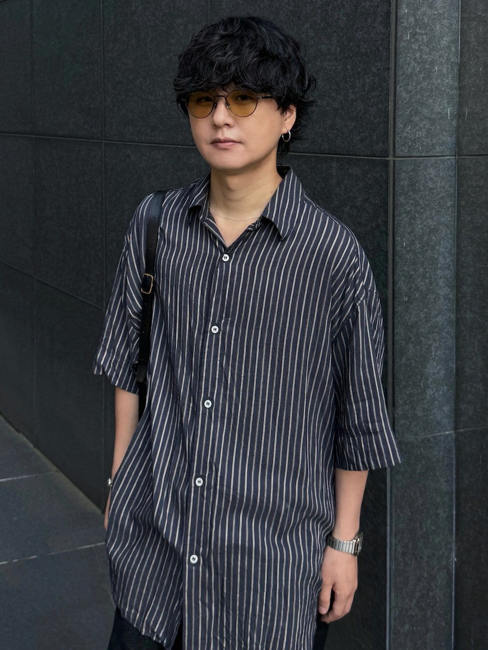 ブラック系のデニムパンツ、ブラック系のドレスシューズ、シルバー系のブレスレットを着用したメンズの夏コーディネートの3枚目の写真