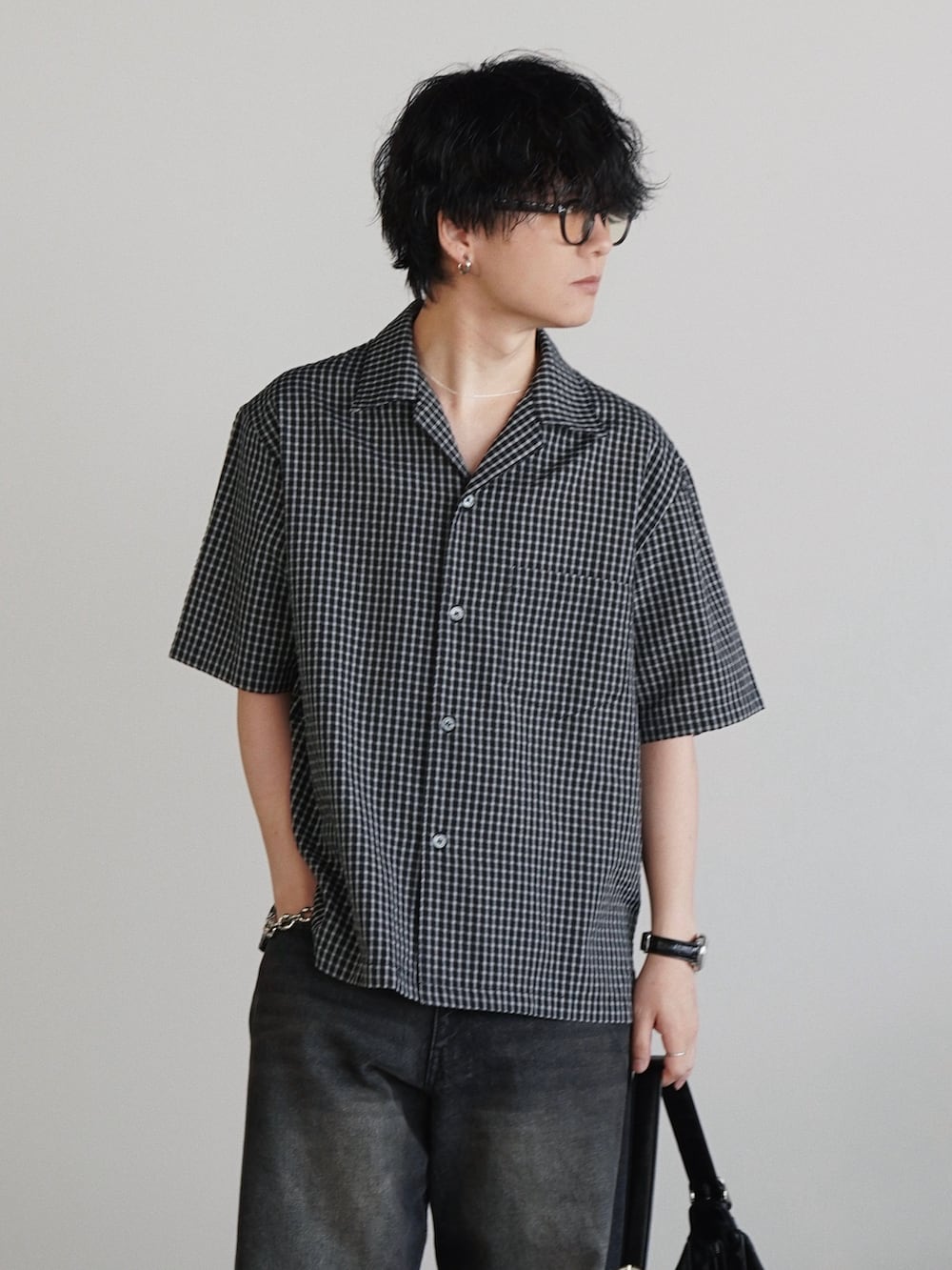 ブラック系のデニムパンツ、ブラック系のショルダーバッグ、ブラック系のドレスシューズを着用したメンズの春コーディネートの3枚目の写真