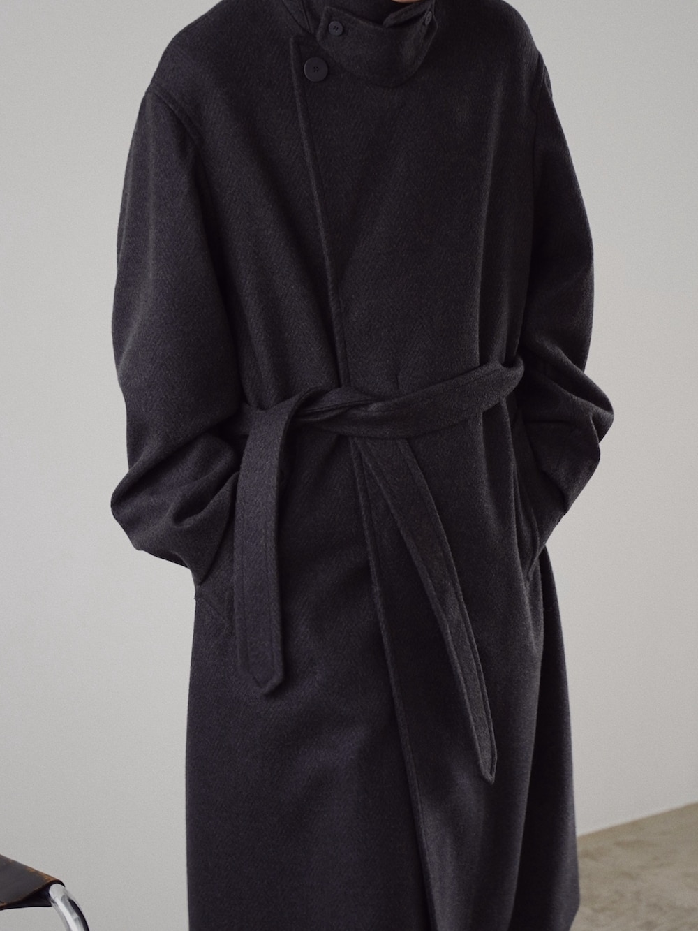 グレー系のチェスターコート、ブルー系のニット/セーター、ブラック系のスラックスを着用したメンズの冬コーディネートの5枚目の写真