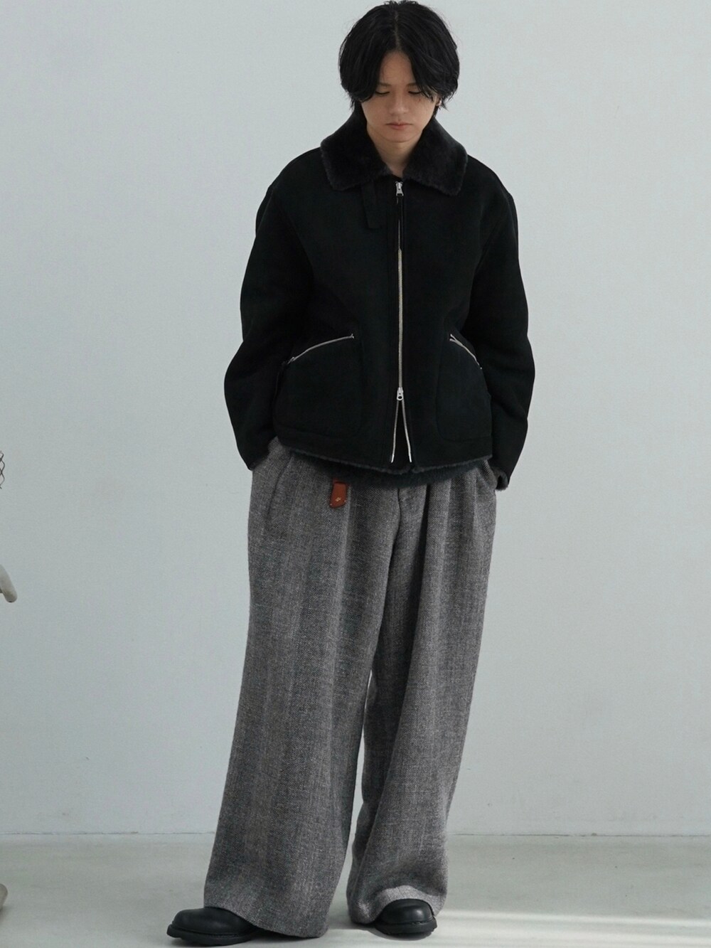 ブラック系のムートンコート、ブラック系のニット/セーター、グレー系のその他パンツを着用したメンズの秋コーディネートの2枚目の写真