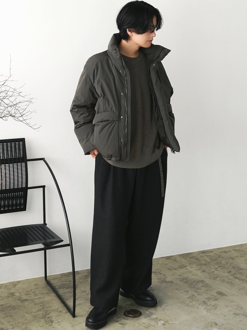 グリーン系のダウンジャケット/コート、ブラウン系のニット/セーター、グレー系のスラックスを着用したメンズの秋コーディネートの2枚目の写真