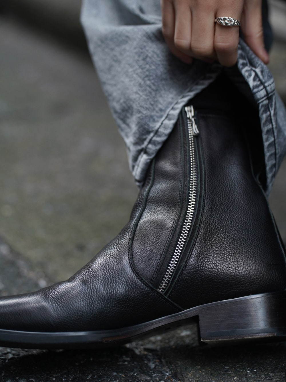 ブラック系のチェスターコート、ブラック系のTシャツ/カットソー、ブラック系のブーツを着用したメンズの冬コーディネートの5枚目の写真
