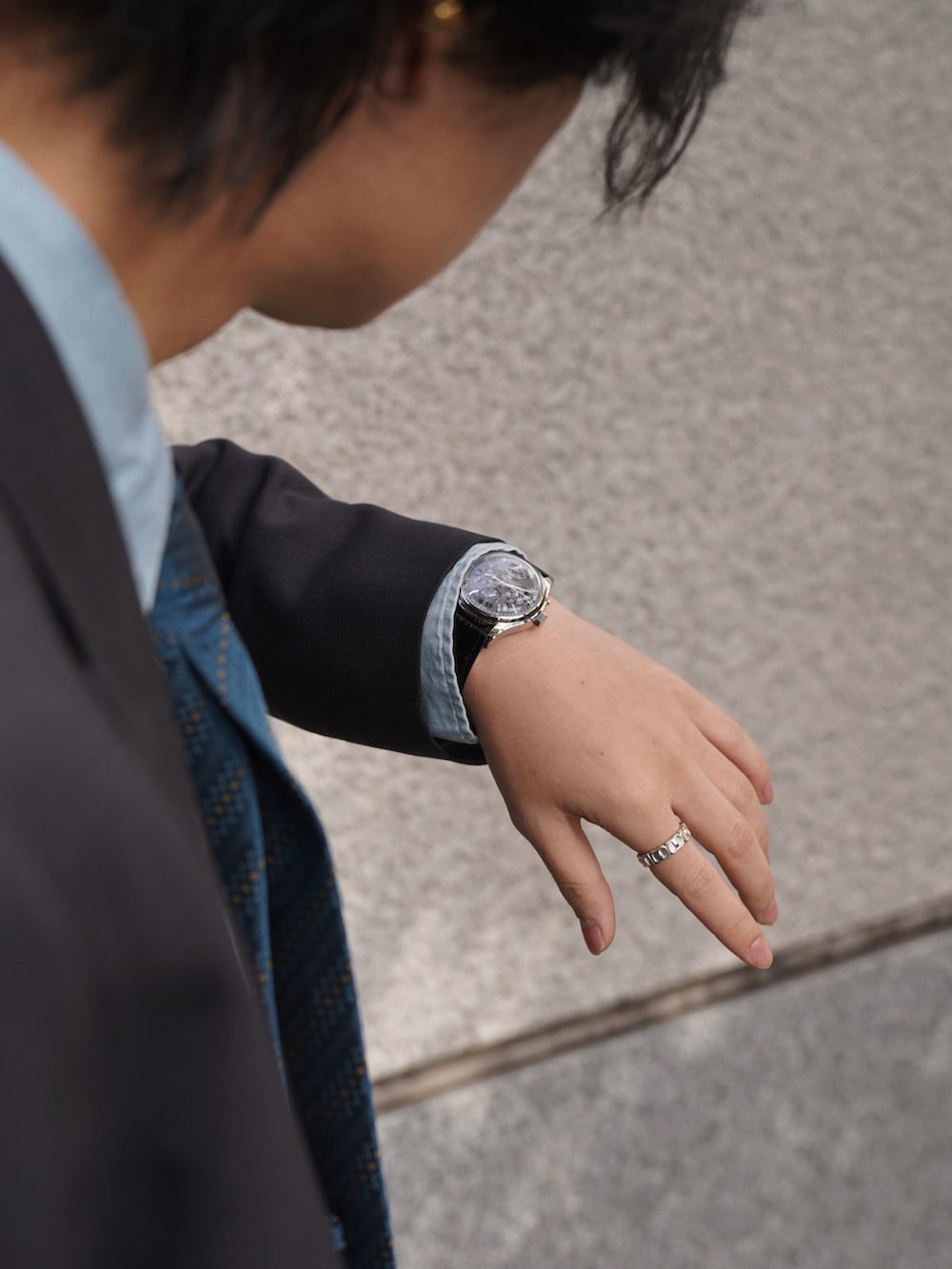 グレー系のテーラードジャケット、グレー系のスラックス、シルバー系のピアス(両耳用)を着用したメンズの冬コーディネートの4枚目の写真