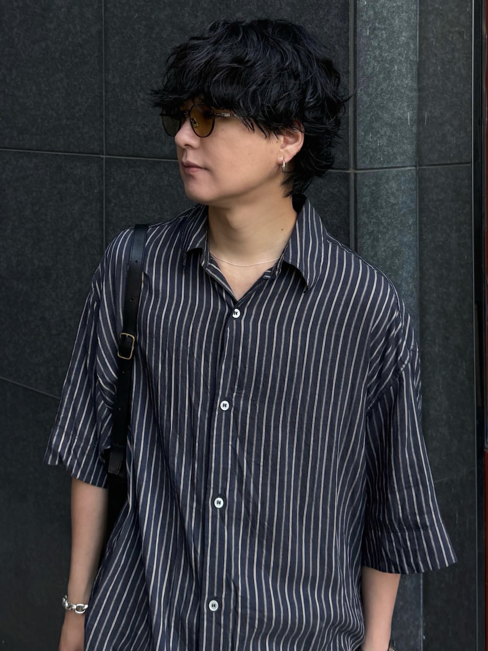 ブラック系のデニムパンツ、ブラック系のドレスシューズ、シルバー系のブレスレットを着用したメンズの夏コーディネートの5枚目の写真