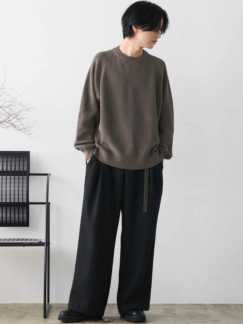 グリーン系のダウンジャケット/コート、ブラウン系のニット/セーター、グレー系のスラックスを着用したメンズの秋コーディネートの3枚目の写真