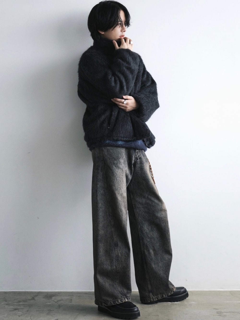 グレー系のブルゾン、ブルー系のニット/セーター、ブルー系のデニムパンツを着用したメンズの冬コーディネートの3枚目の写真