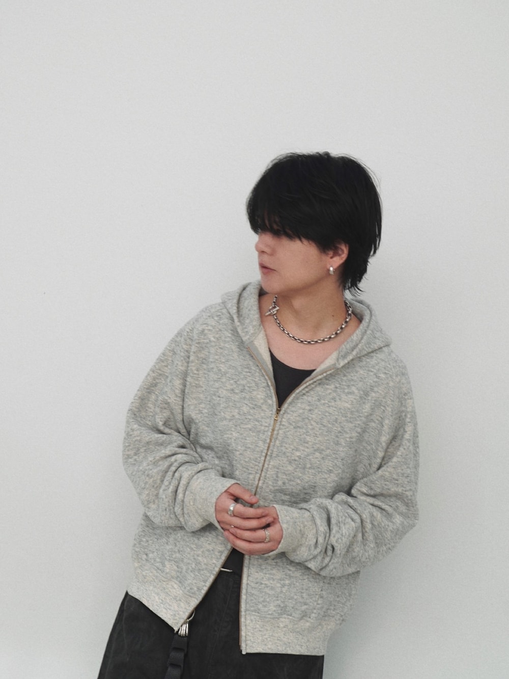 グレー系のパーカー、グレー系のTシャツ/カットソー、ブラック系のスラックスを着用したメンズの冬コーディネートの3枚目の写真