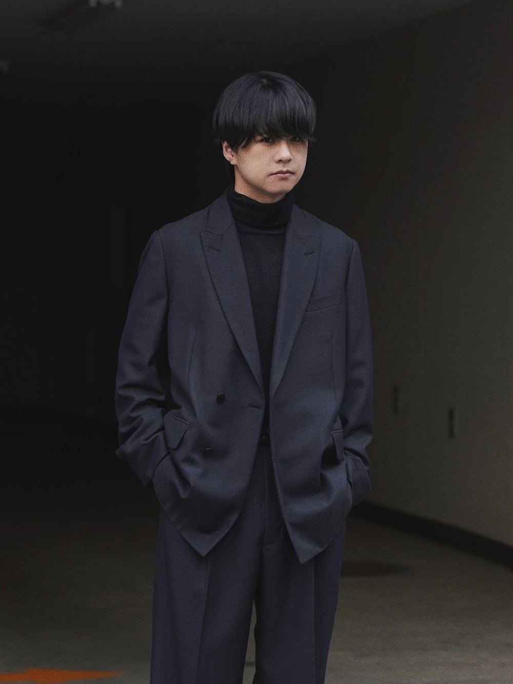 ブラック系のテーラードジャケット、グレー系のニット/セーター、ブラック系のスラックスを着用したメンズの冬コーディネートの2枚目の写真