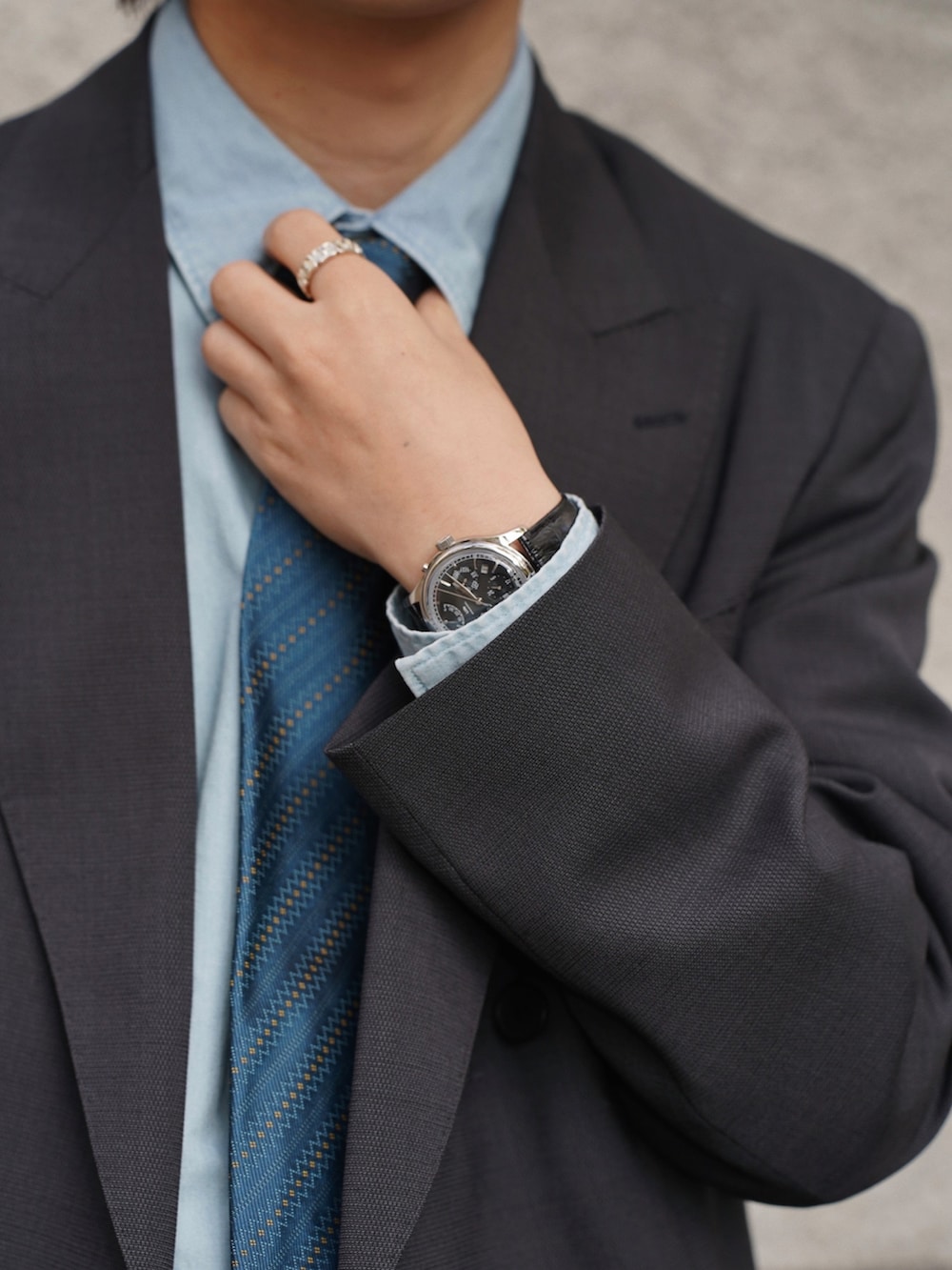 グレー系のテーラードジャケット、グレー系のスラックス、シルバー系のピアス(両耳用)を着用したメンズの冬コーディネートの3枚目の写真