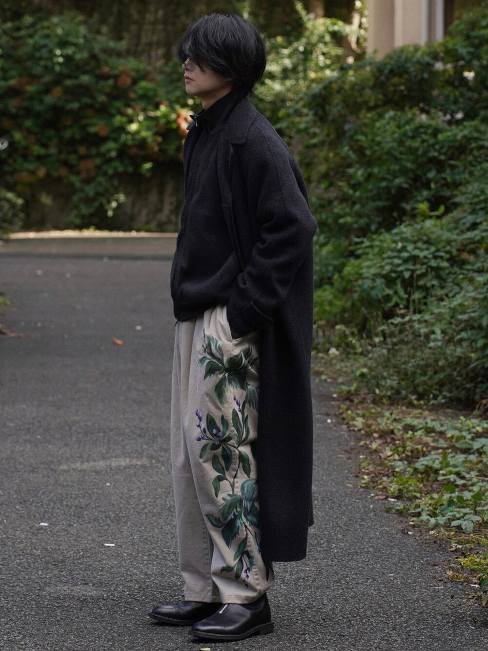 ブラック系のチェスターコート、ブラック系のトップス、グレー系のパンツを着用したメンズの秋コーディネートの2枚目の写真