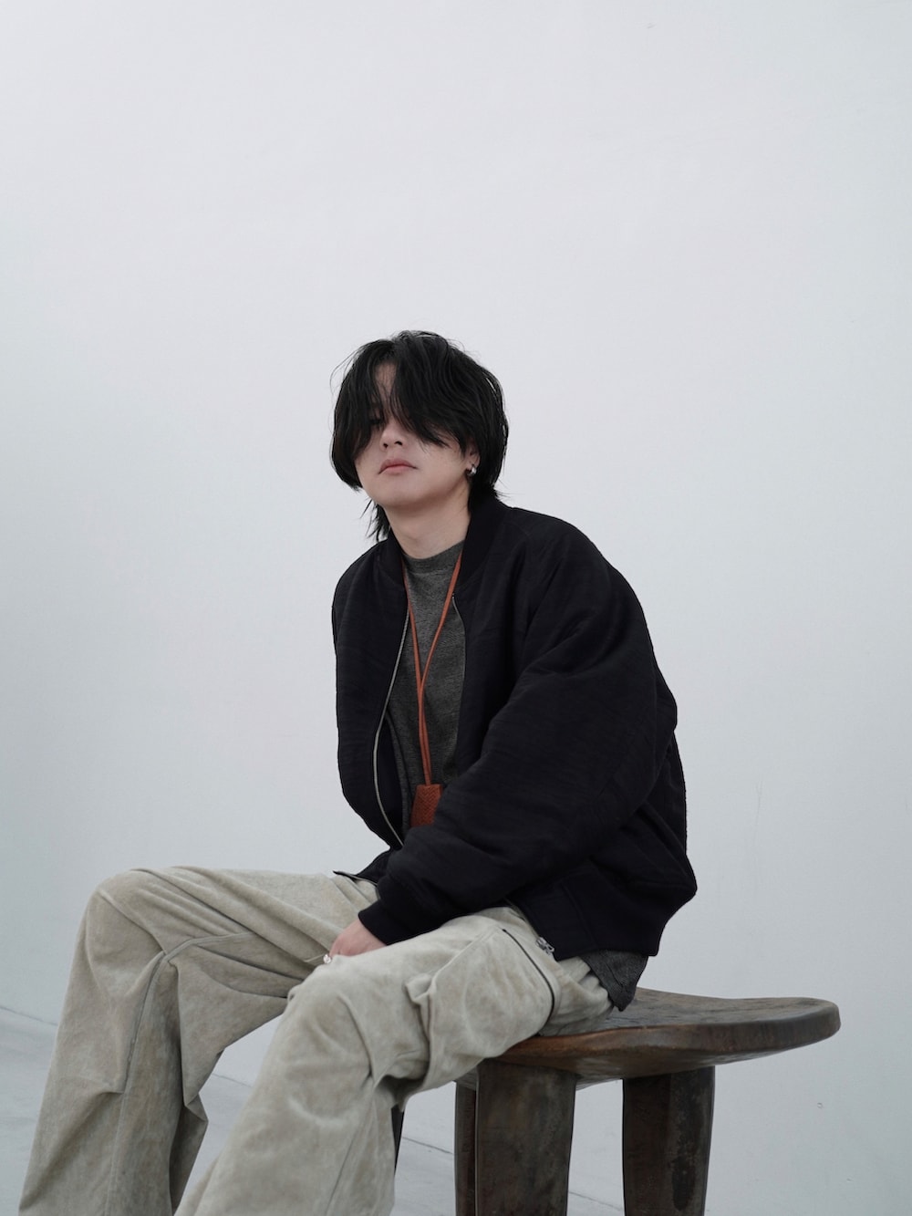 ブラック系のMA-1、ベージュ系のカーゴパンツ、イエロー系のTシャツ/カットソーを着用したメンズの夏コーディネートの3枚目の写真