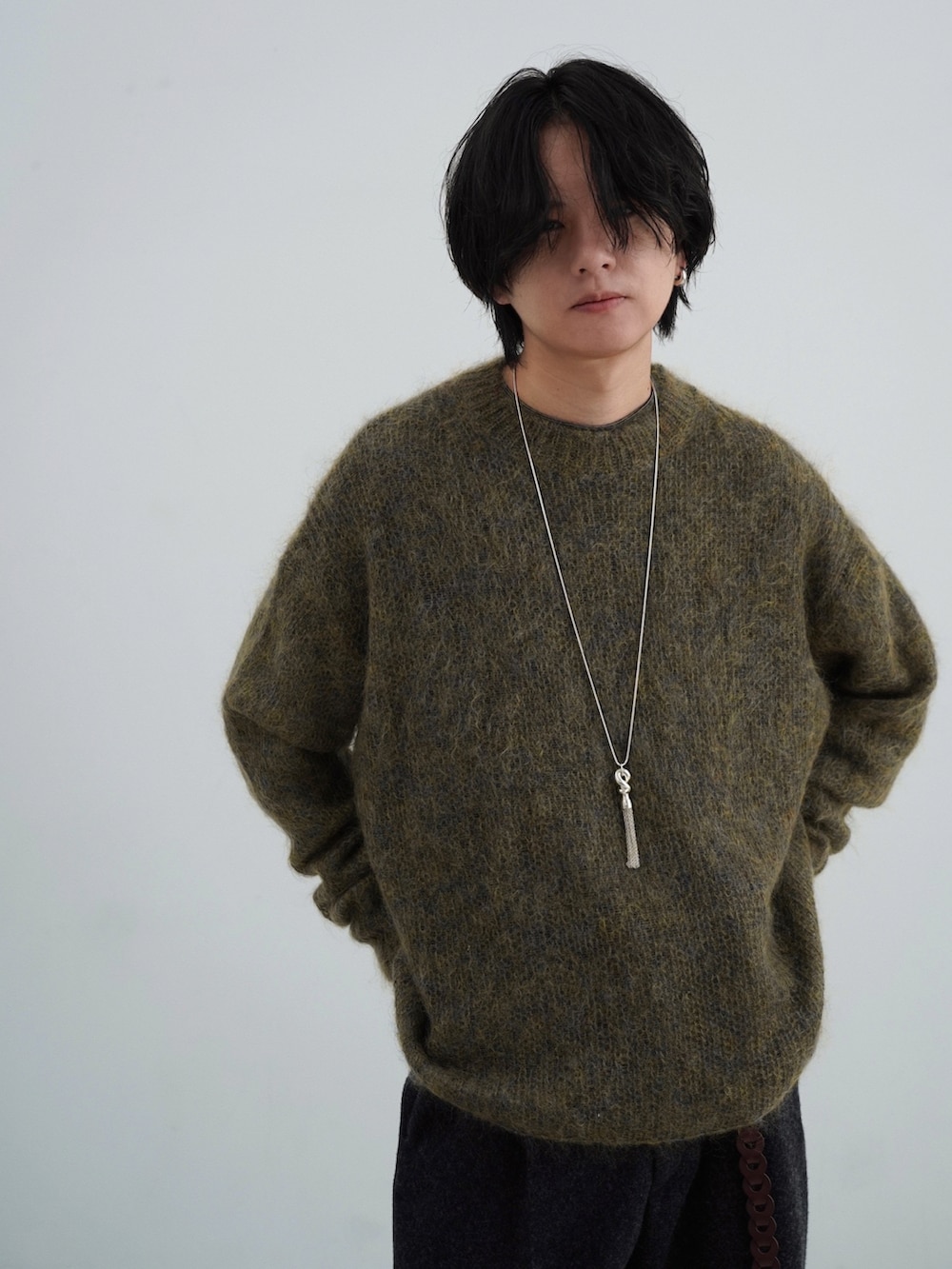 ブラック系のダウンジャケット/コート、グリーン系のニット/セーター、グレー系のスラックスを着用したメンズの秋コーディネートの5枚目の写真