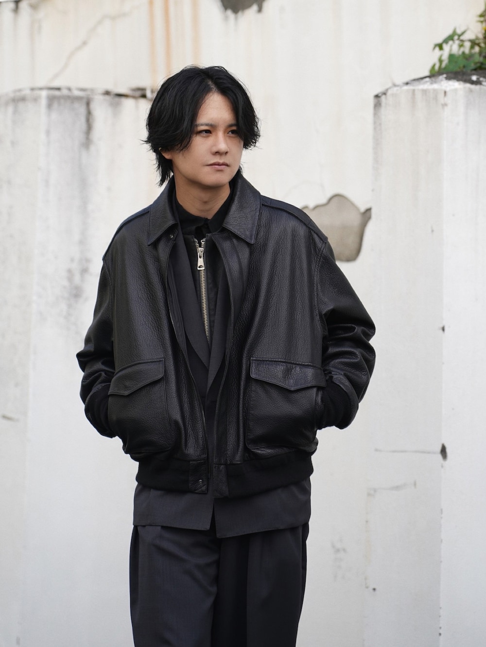 ブラック系のブルゾン、グレー系のテーラードジャケット、グレー系のスラックスを着用したメンズの冬コーディネートの3枚目の写真