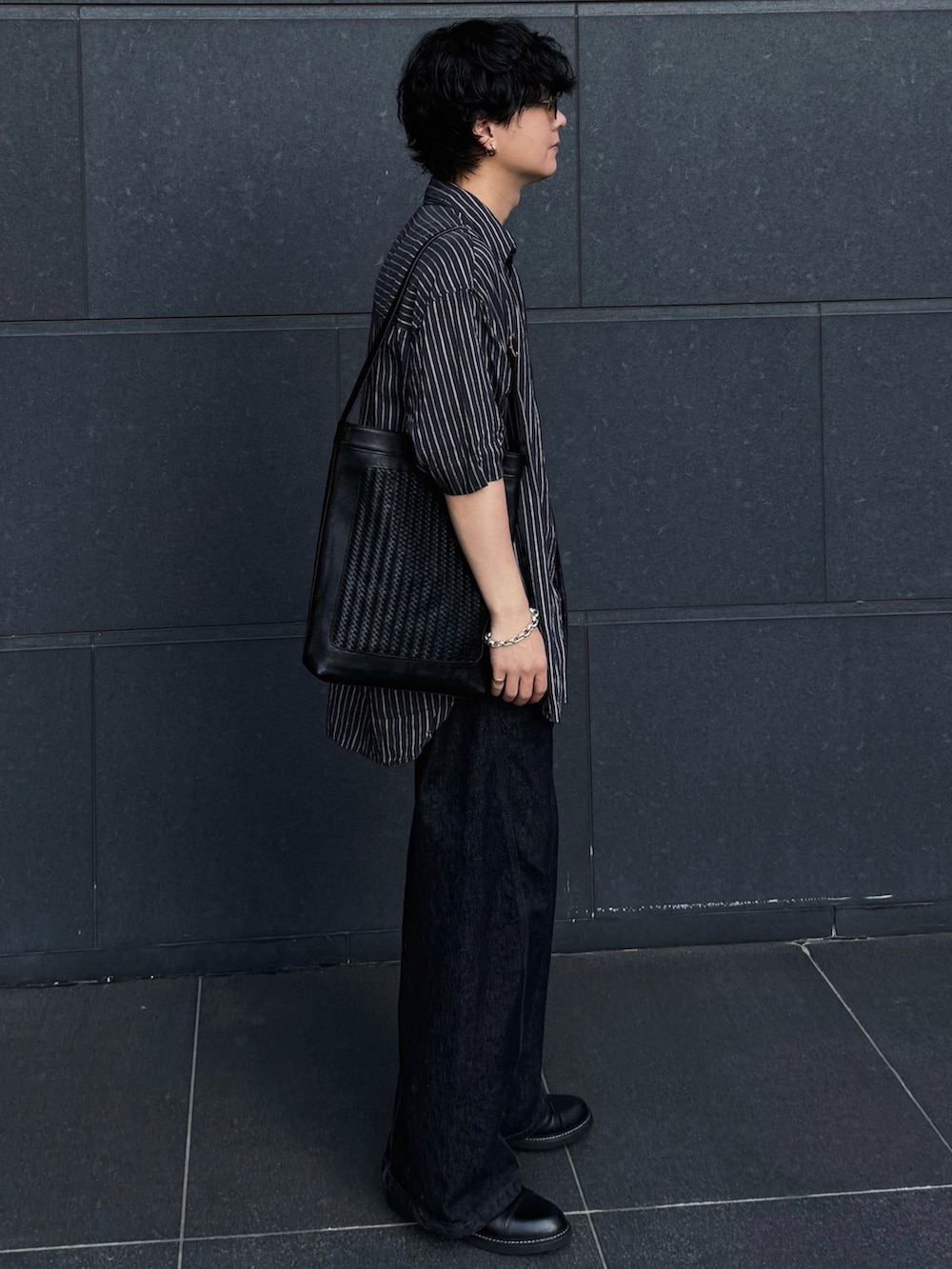 ブラック系のデニムパンツ、ブラック系のドレスシューズ、シルバー系のブレスレットを着用したメンズの夏コーディネートの2枚目の写真