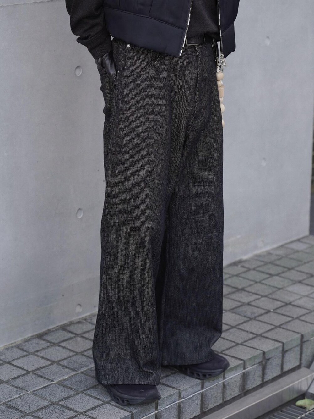 ブラック系のベスト、グレー系のニット/セーター、ブラック系のデニムパンツを着用したメンズの冬コーディネートの5枚目の写真