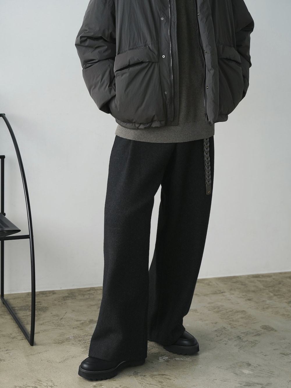 グリーン系のダウンジャケット/コート、ブラウン系のニット/セーター、グレー系のスラックスを着用したメンズの秋コーディネートの4枚目の写真