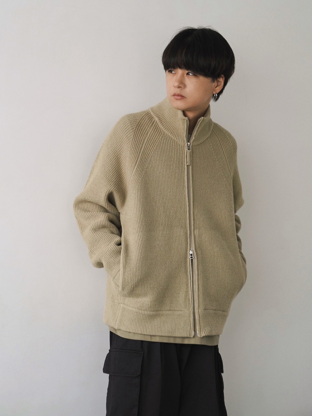 ベージュ系のカーディガン/ボレロ、ベージュ系のTシャツ/カットソー、グレー系のカーゴパンツを着用したメンズの冬コーディネートの2枚目の写真