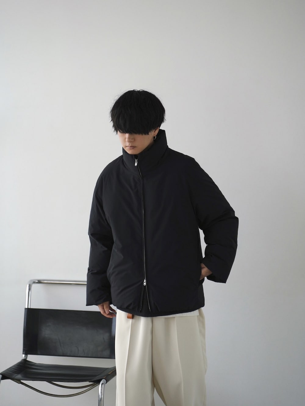 ブラック系のダウンジャケット/コート、グレー系のニット/セーター、ホワイト系のタンクトップを着用したメンズの秋コーディネートの5枚目の写真