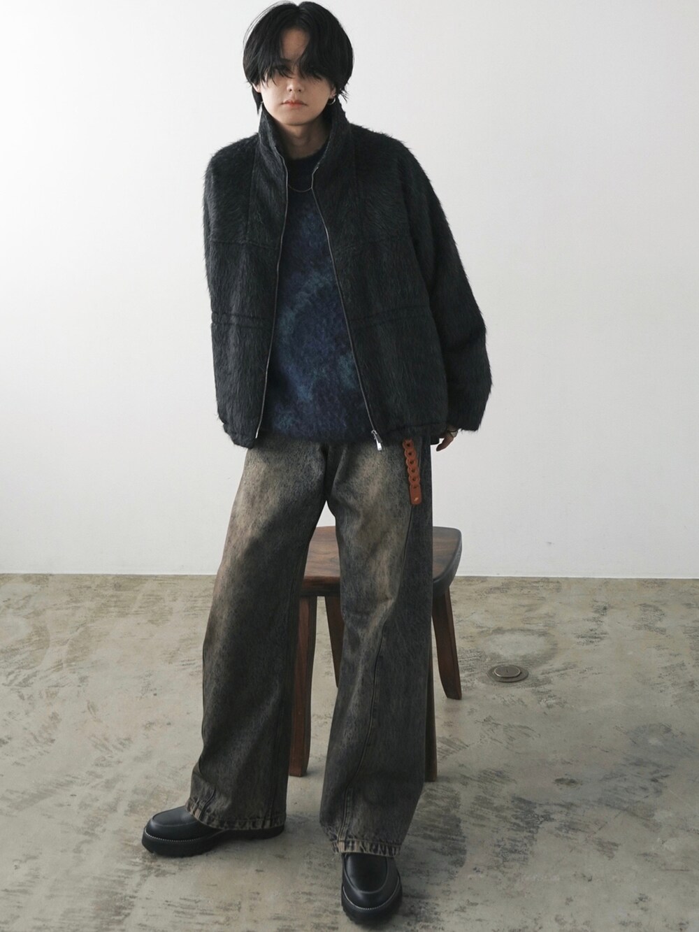 グレー系のブルゾン、ブルー系のニット/セーター、ブルー系のデニムパンツを着用したメンズの冬コーディネートの2枚目の写真