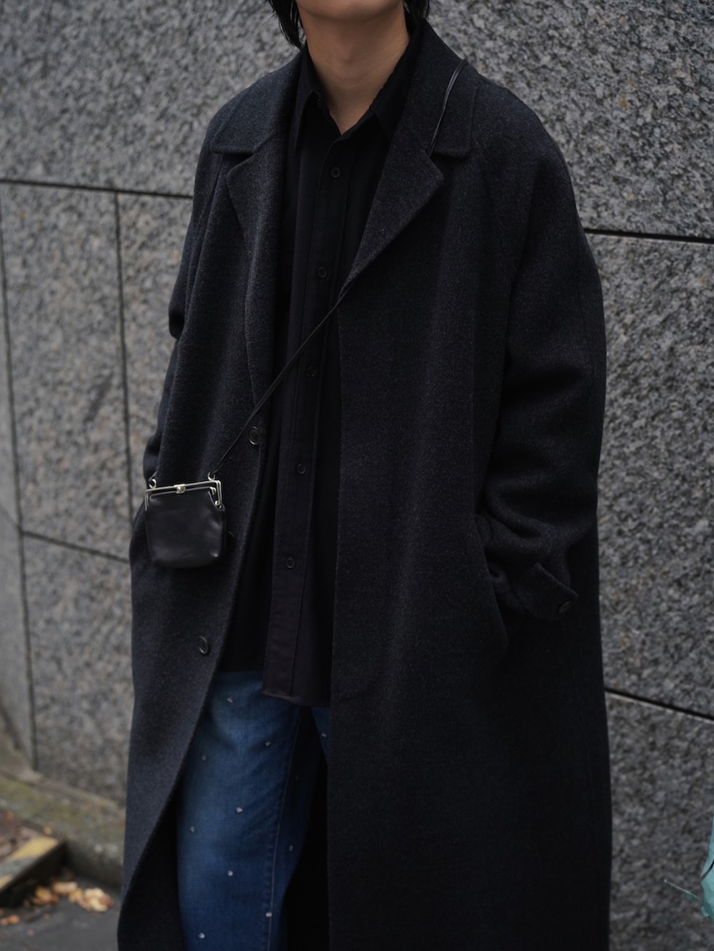 ブラック系のチェスターコート、ブラウン系のシャツ/ブラウス、ブルー系のパンツを着用したメンズの冬コーディネートの2枚目の写真