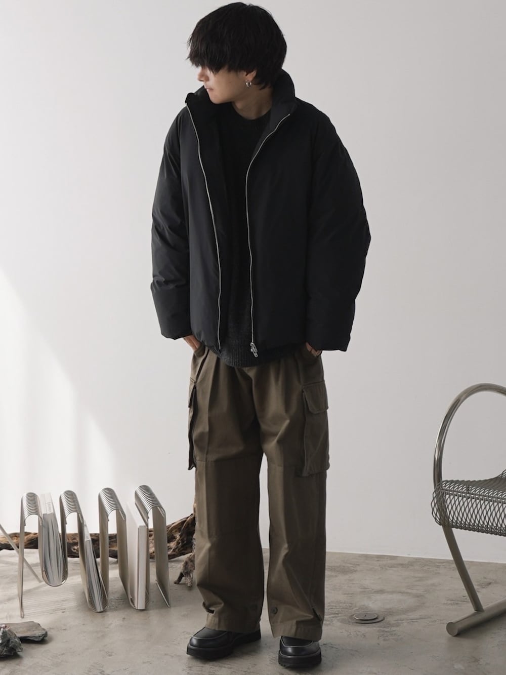 ブラック系のダウンジャケット/コート、グレー系のニット/セーター、グリーン系のカーゴパンツを着用したメンズの秋コーディネートの3枚目の写真