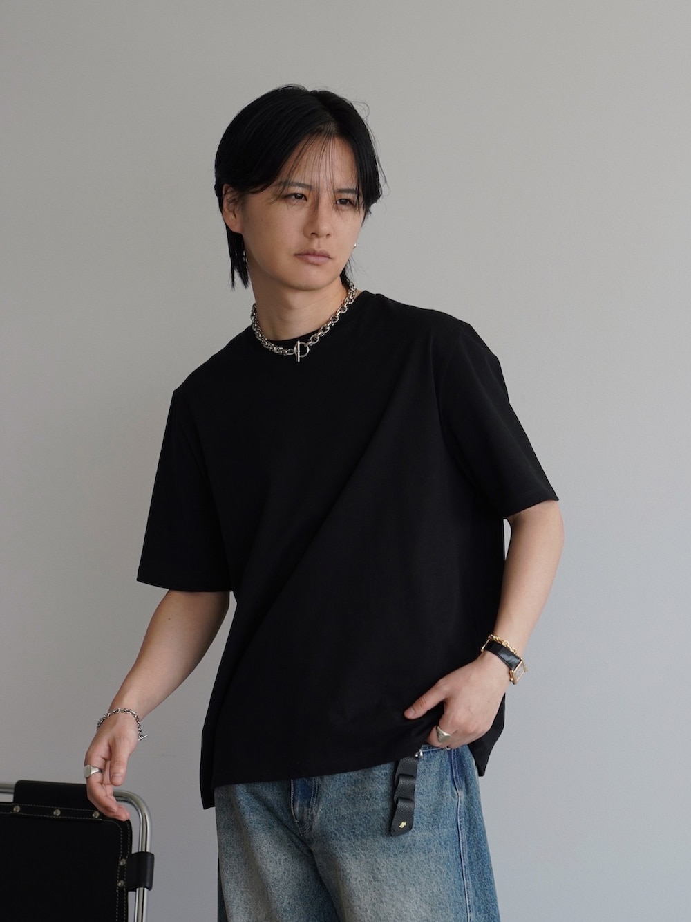 ブラック系のTシャツ/カットソー、ブルー系のデニムパンツ、ブラック系のドレスシューズを着用したメンズの春コーディネートの2枚目の写真