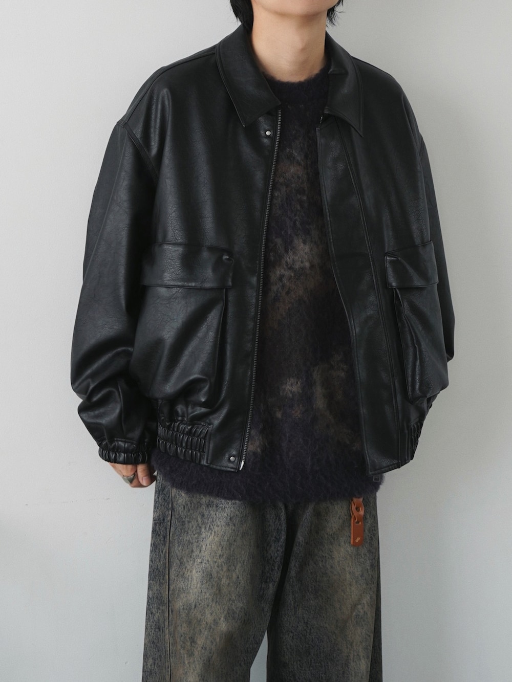 ブラック系のブルゾン、ブルー系のニット/セーター、ブルー系のデニムパンツを着用したメンズの秋コーディネートの3枚目の写真