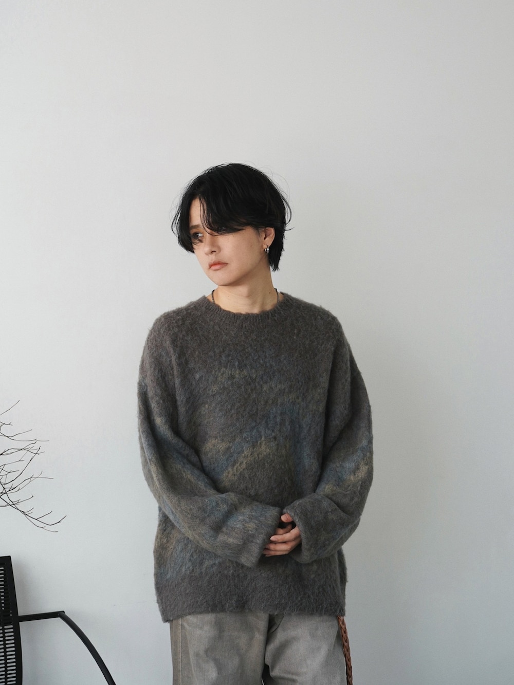 グレー系のダウンジャケット/コート、グリーン系のニット/セーター、ブラウン系のデニムパンツを着用したメンズの秋コーディネートの4枚目の写真