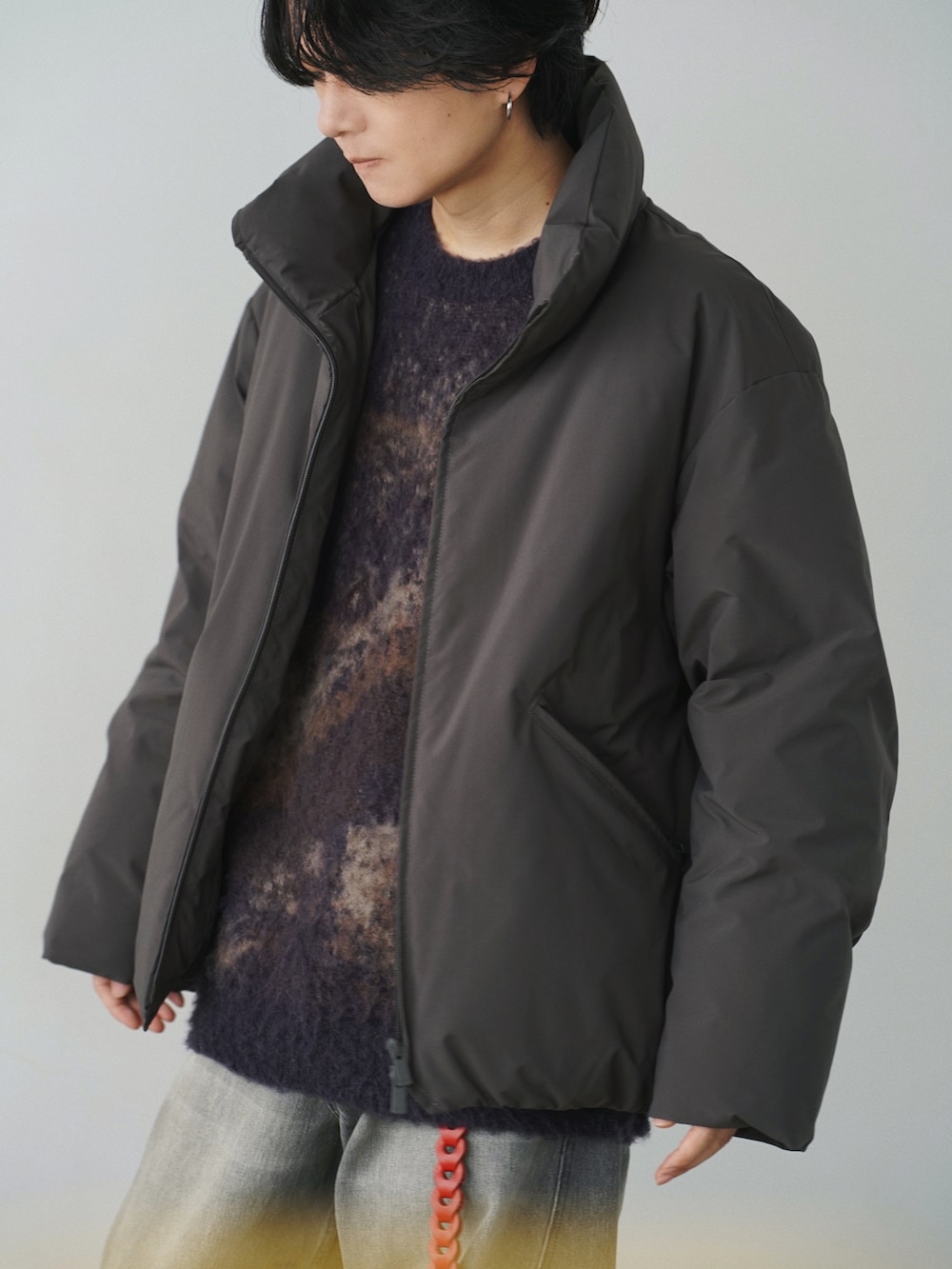 ブラウン系のダウンジャケット/コート、ブラウン系のニット/セーター、グレー系のデニムパンツを着用したメンズの冬コーディネートの2枚目の写真