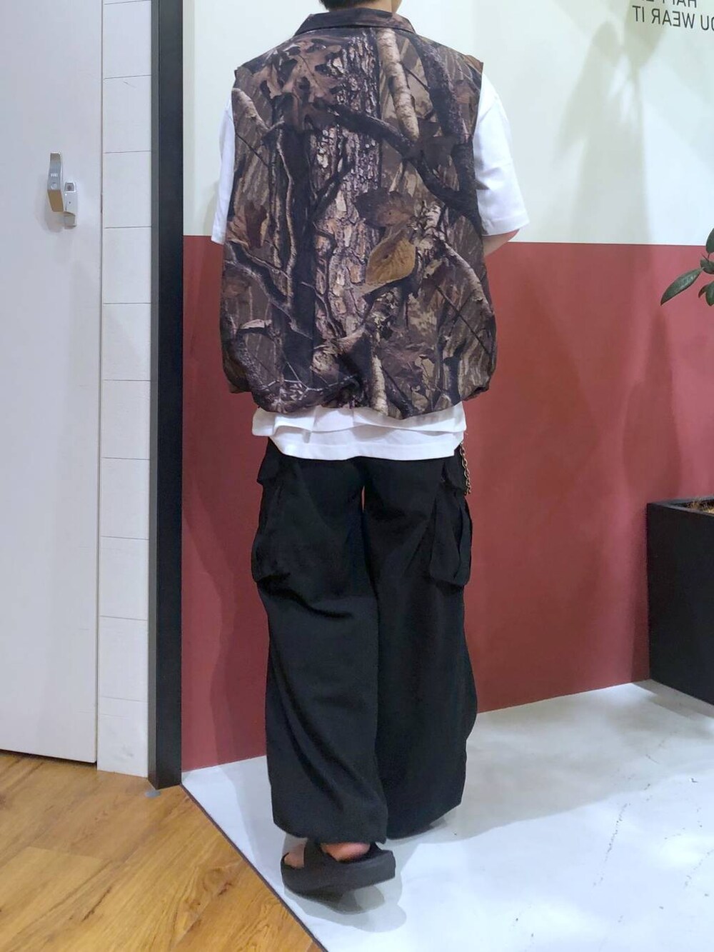 ブラウン系のベスト、ホワイト系のタンクトップ、ブラック系のサンダルを着用したメンズの秋コーディネートの3枚目の写真