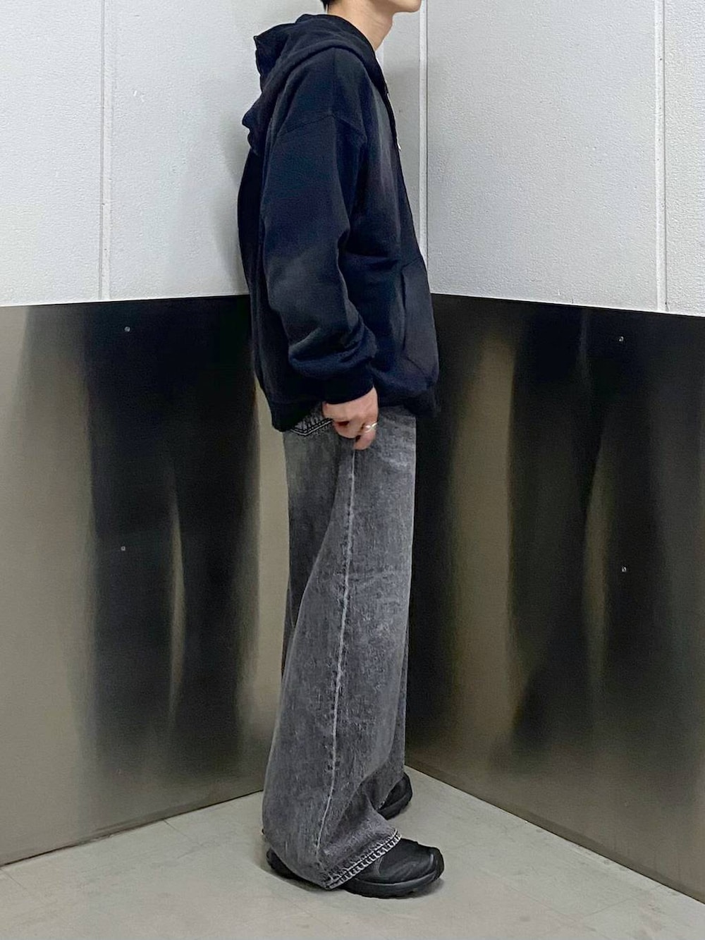 ブラック系のスニーカー、ブラック系のパーカー、グレー系のデニムパンツを着用したメンズの春コーディネートの4枚目の写真