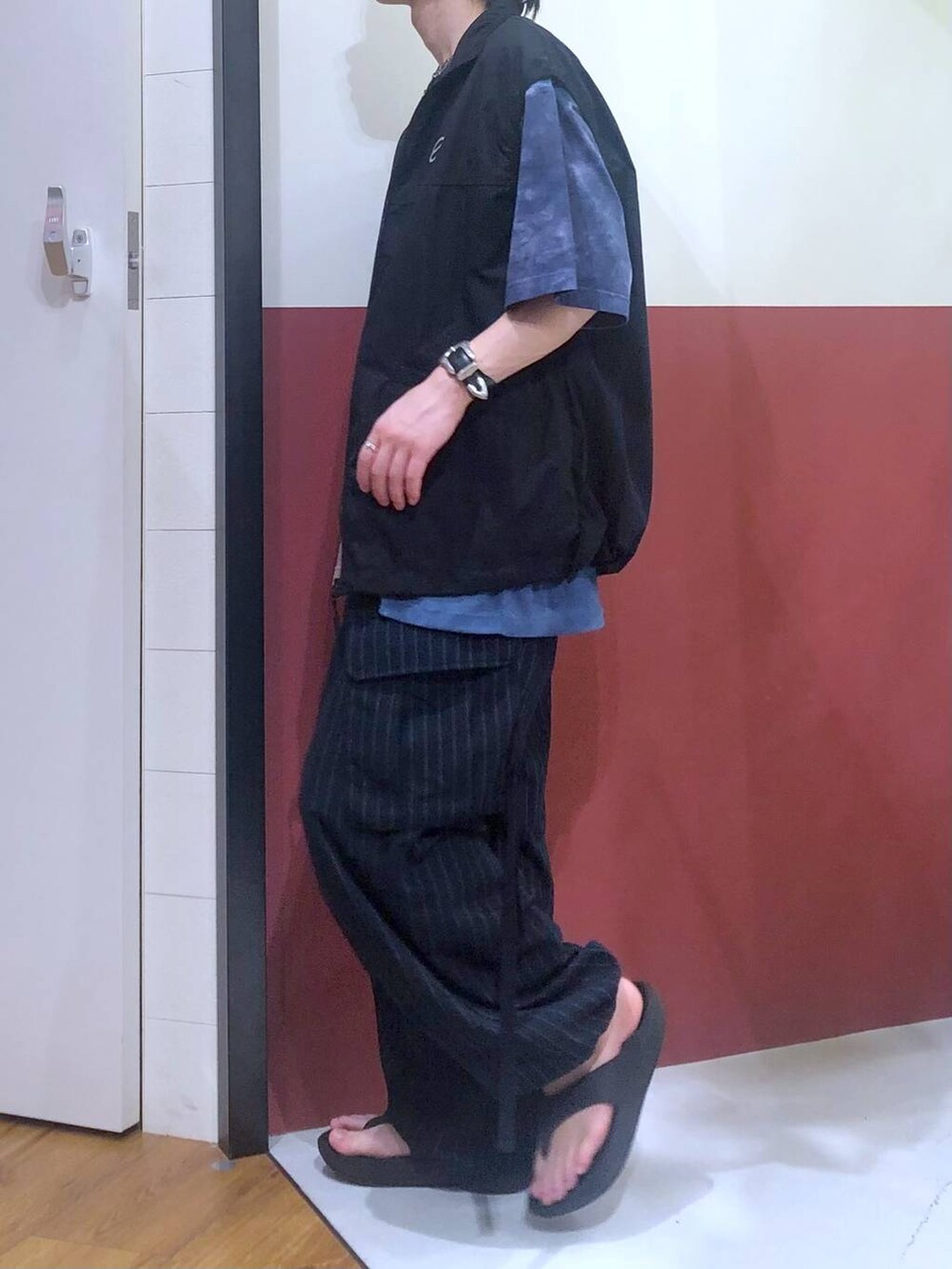 ブラック系のタンクトップ、ブルー系のカーゴパンツ、ブラック系のサンダルを着用したメンズの夏コーディネートの2枚目の写真