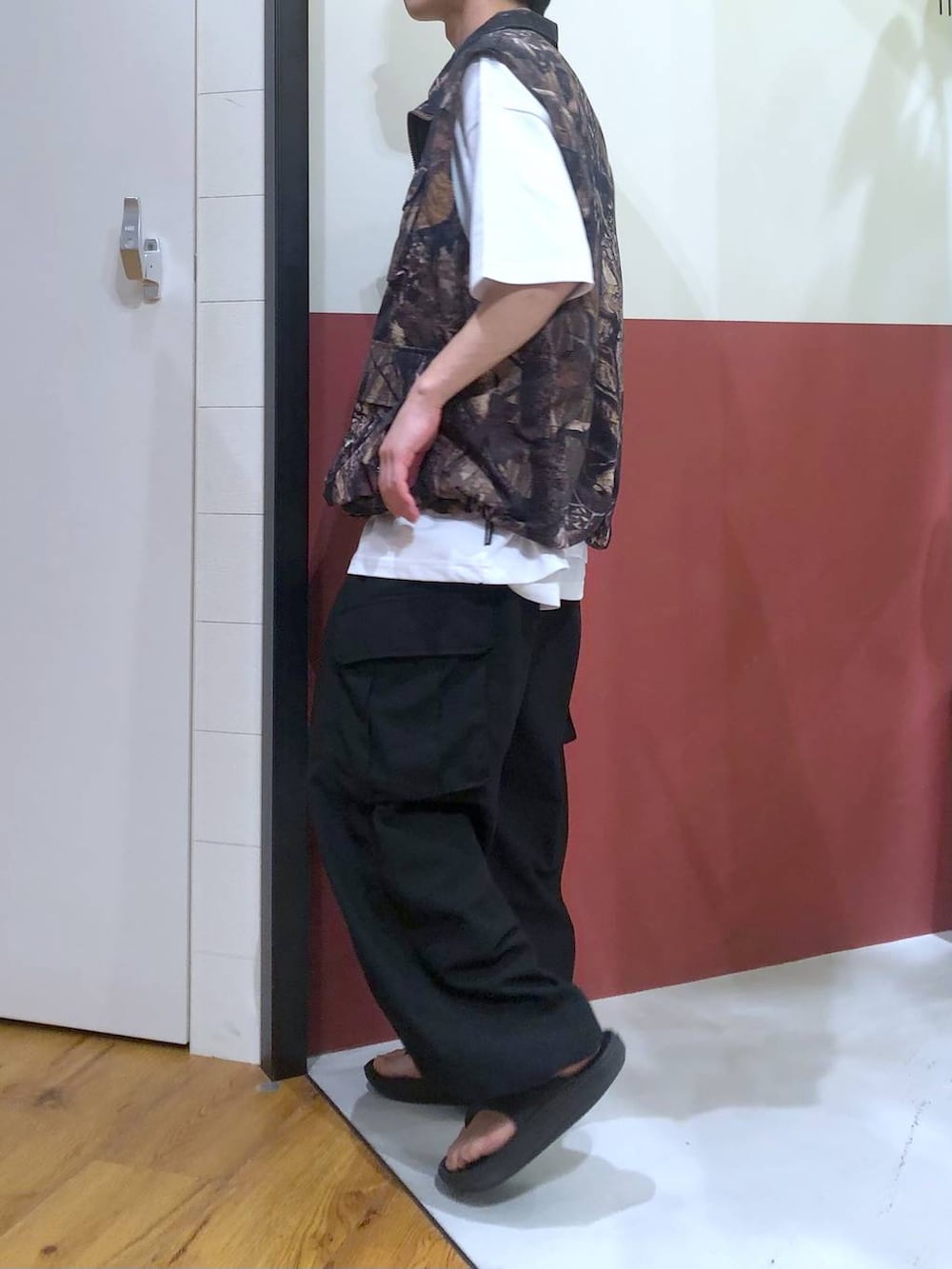 ブラウン系のベスト、ホワイト系のタンクトップ、ブラック系のサンダルを着用したメンズの秋コーディネートの2枚目の写真