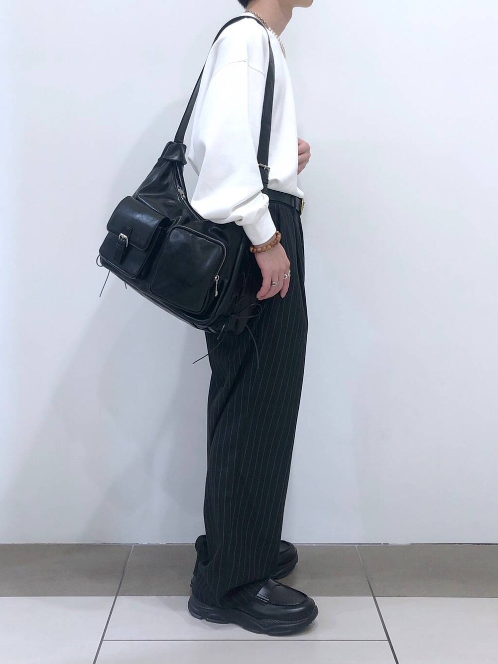 ブラック系のスラックス、ブラック系のショルダーバッグ、ブラック系のローファーを着用したメンズの秋コーディネートの3枚目の写真