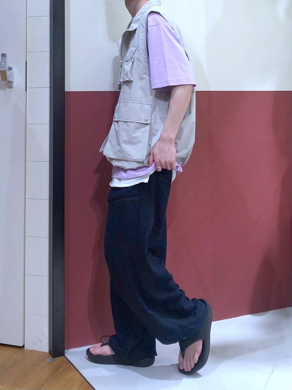 グレー系のベスト、ホワイト系のタンクトップ、ブラック系のサンダルを着用したメンズの夏コーディネートの2枚目の写真