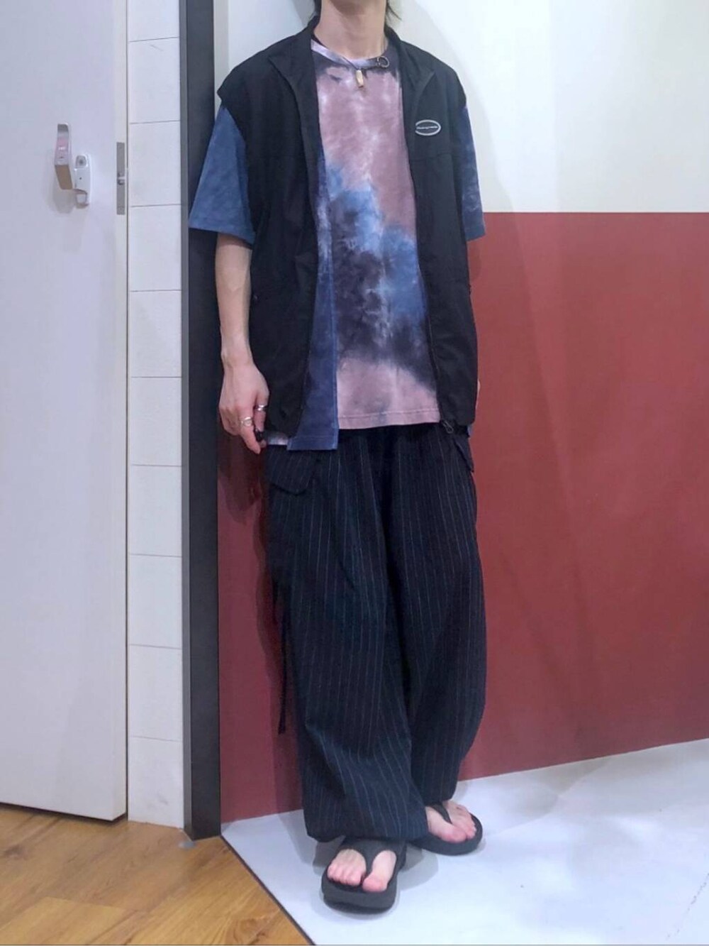 ブラック系のタンクトップ、ブルー系のカーゴパンツ、ブラック系のサンダルを着用したメンズの夏コーディネートの5枚目の写真