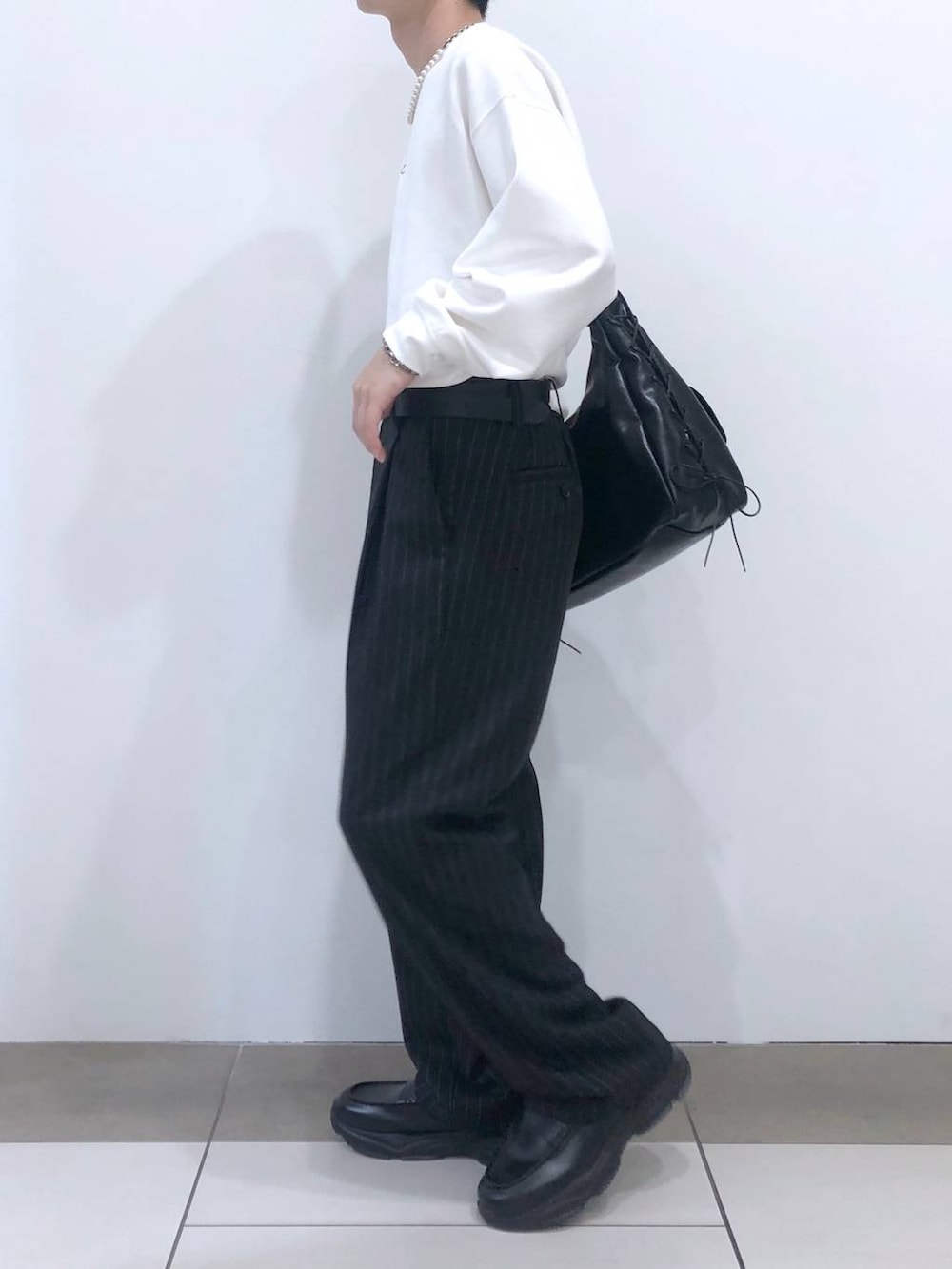 ブラック系のスラックス、ブラック系のショルダーバッグ、ブラック系のローファーを着用したメンズの秋コーディネートの2枚目の写真