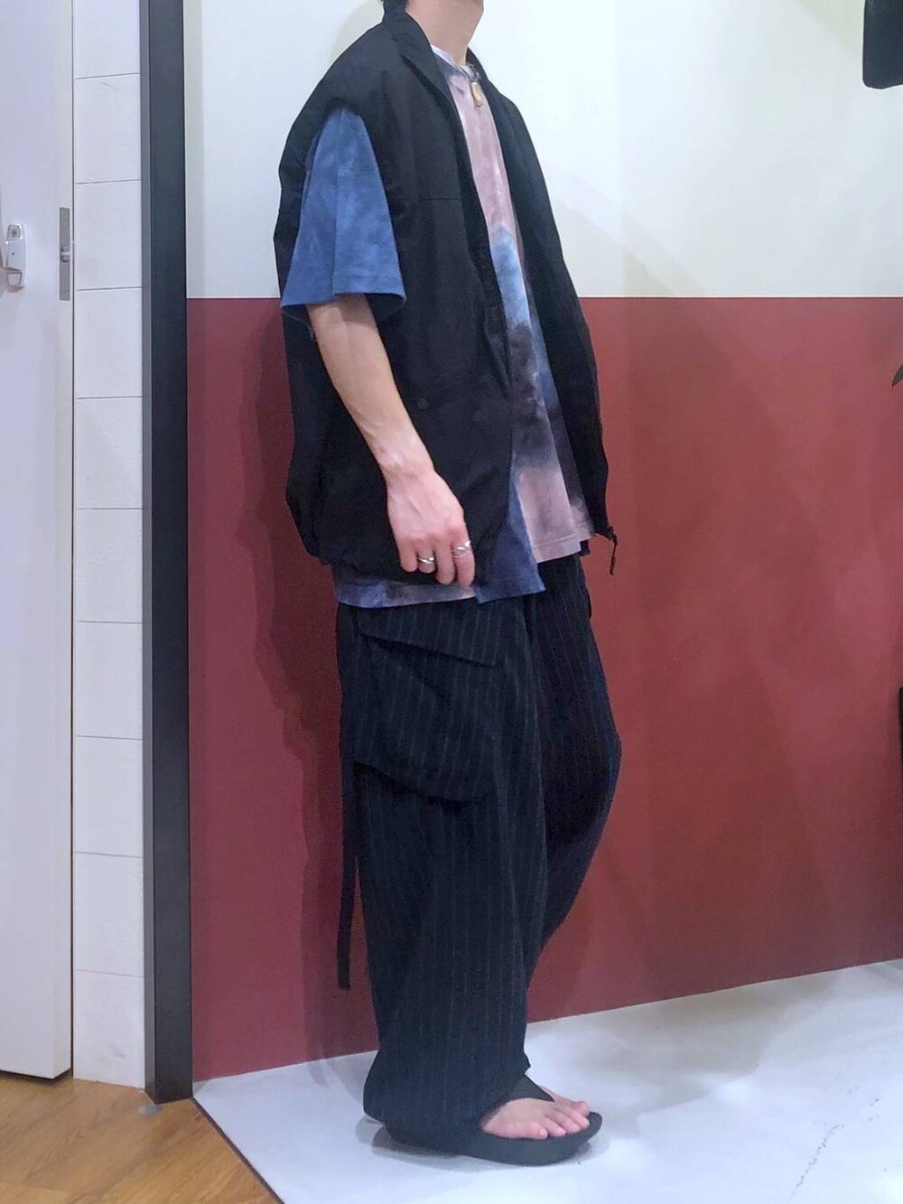 ブラック系のタンクトップ、ブルー系のカーゴパンツ、ブラック系のサンダルを着用したメンズの夏コーディネートの4枚目の写真