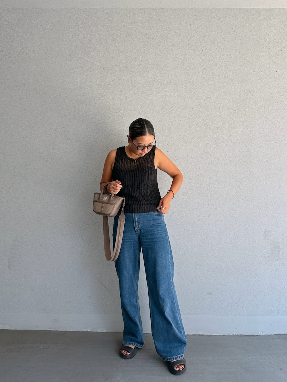 ブラック系のサンダル、ブルー系のデニムパンツ、ブラウン系のショルダーバッグを着用したレディースの夏コーディネートの2枚目の写真