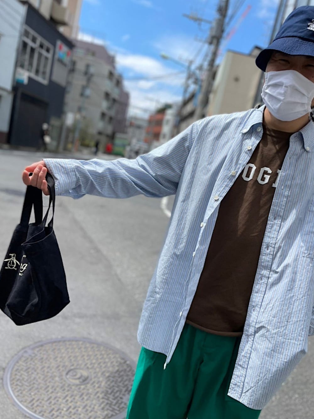 ブラウン系のTシャツ/カットソー、ブラック系のトートバッグ、グリーン系のパンツを着用したメンズの春コーディネートの2枚目の写真