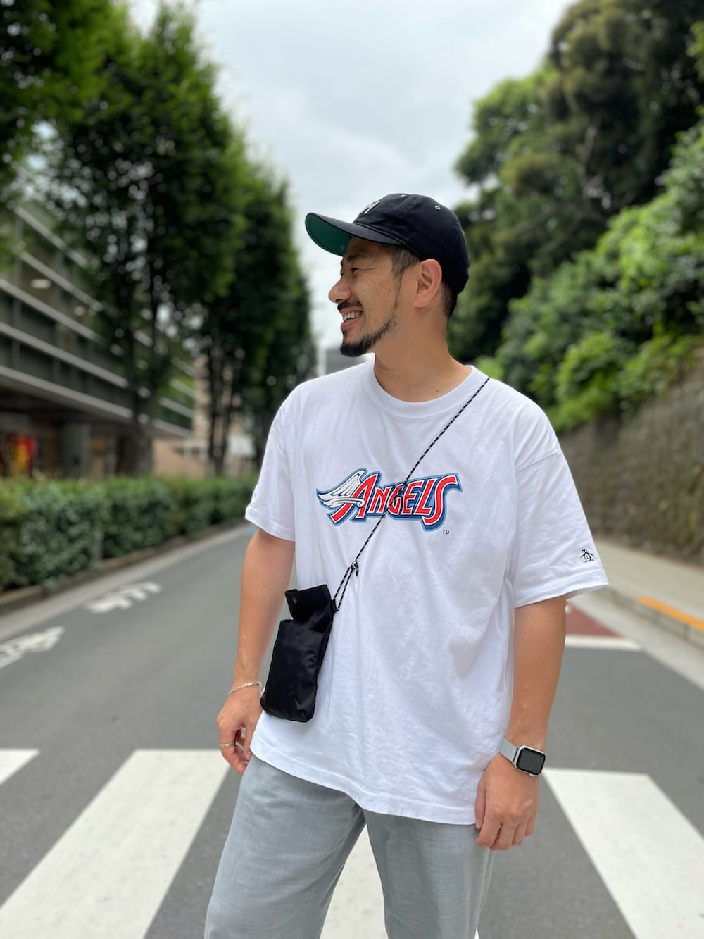 グレー系のスラックス、ホワイト系のTシャツ/カットソー、ブラック系のショルダーバッグを着用したメンズの夏コーディネートの2枚目の写真