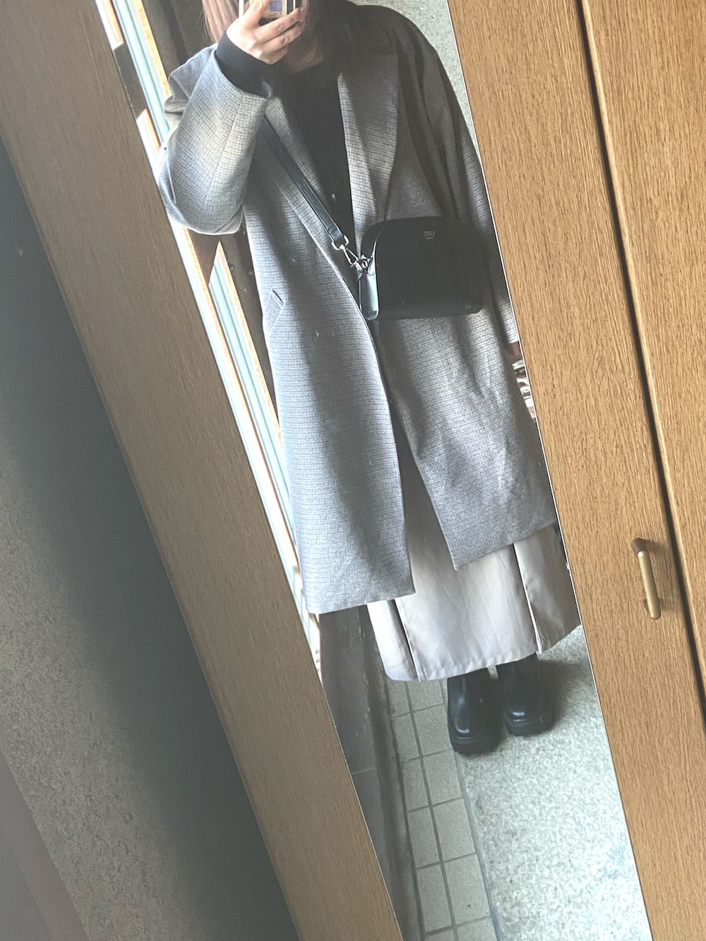 ベージュ系のワンピース、ブラック系のショルダーバッグ、ブラック系のブーツを着用したレディースの冬コーディネートの2枚目の写真