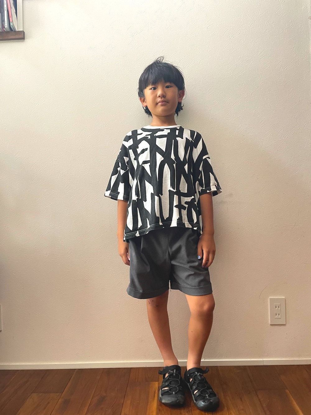 ブラック系のTシャツ/カットソー、ブラック系のサンダルを着用したキッズの夏コーディネートの2枚目の写真
