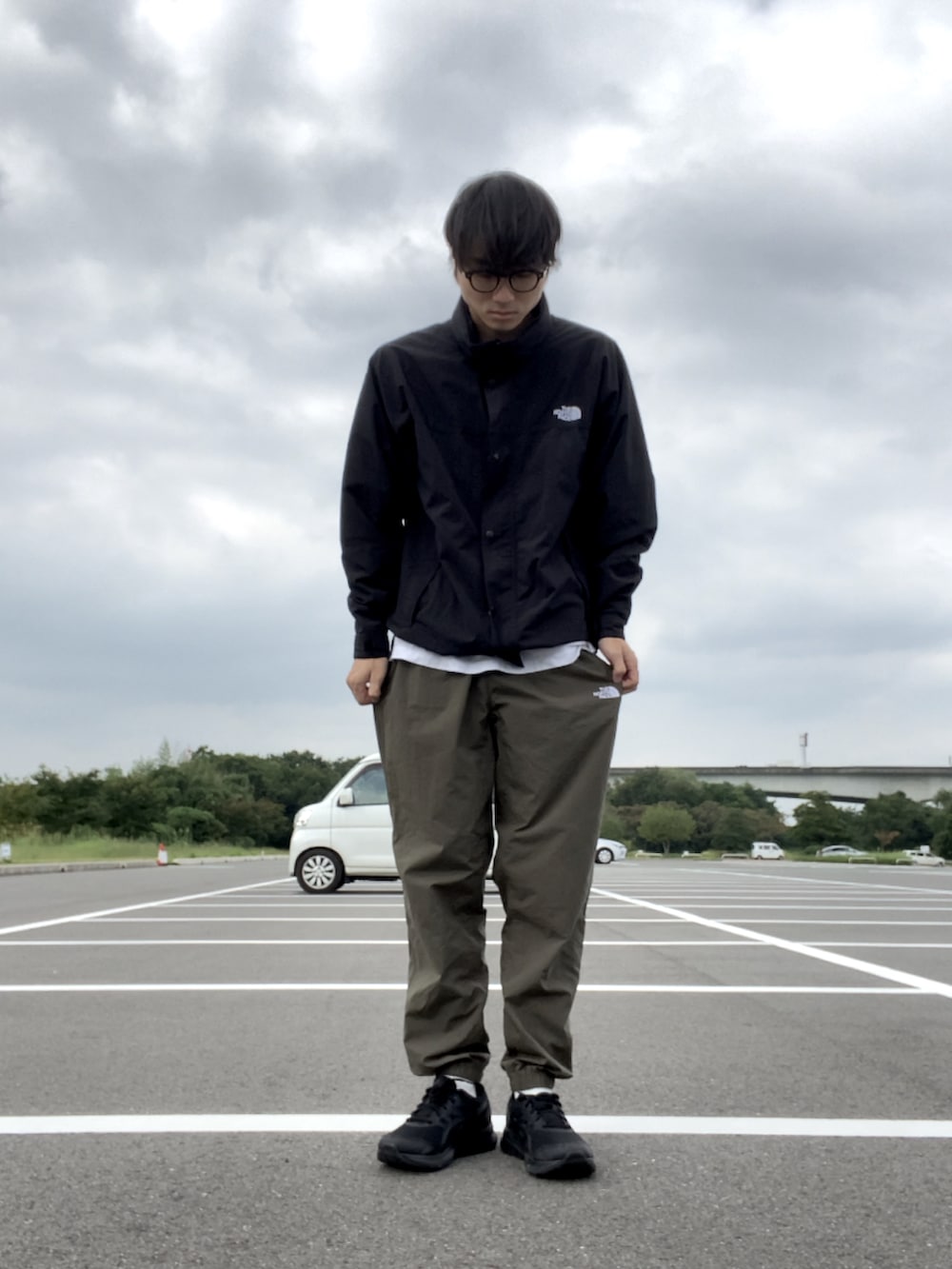 ブラック系のナイロンジャケット、グリーン系のその他パンツ、ブラック系のスニーカーを着用したメンズの秋コーディネートの3枚目の写真