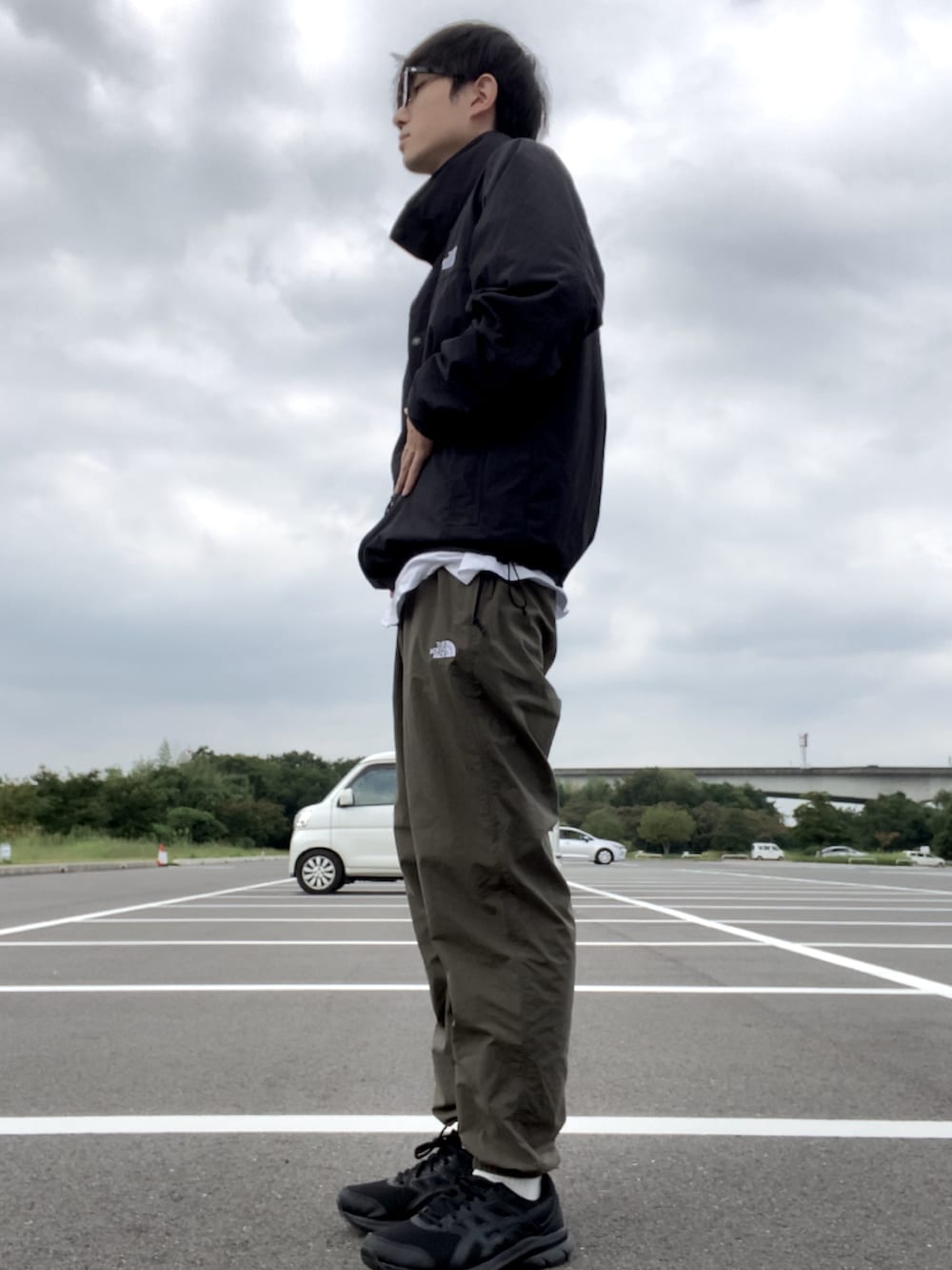 ブラック系のナイロンジャケット、グリーン系のその他パンツ、ブラック系のスニーカーを着用したメンズの秋コーディネートの2枚目の写真