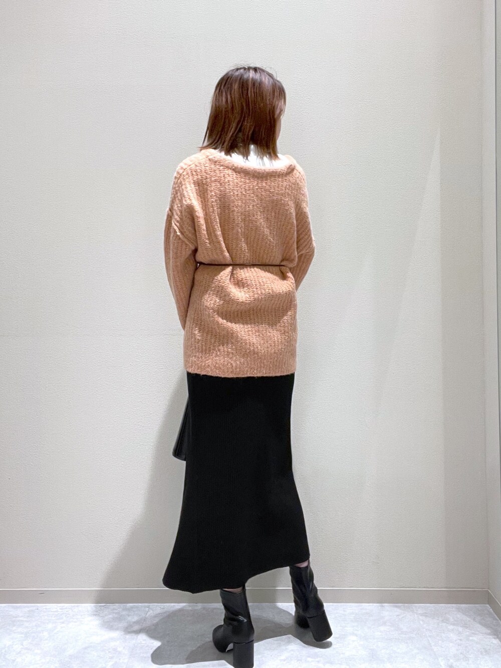 ピンク系のニット/セーター、ブラック系のブーツ、ブラック系のショルダーバッグを着用したレディースの秋コーディネートの2枚目の写真