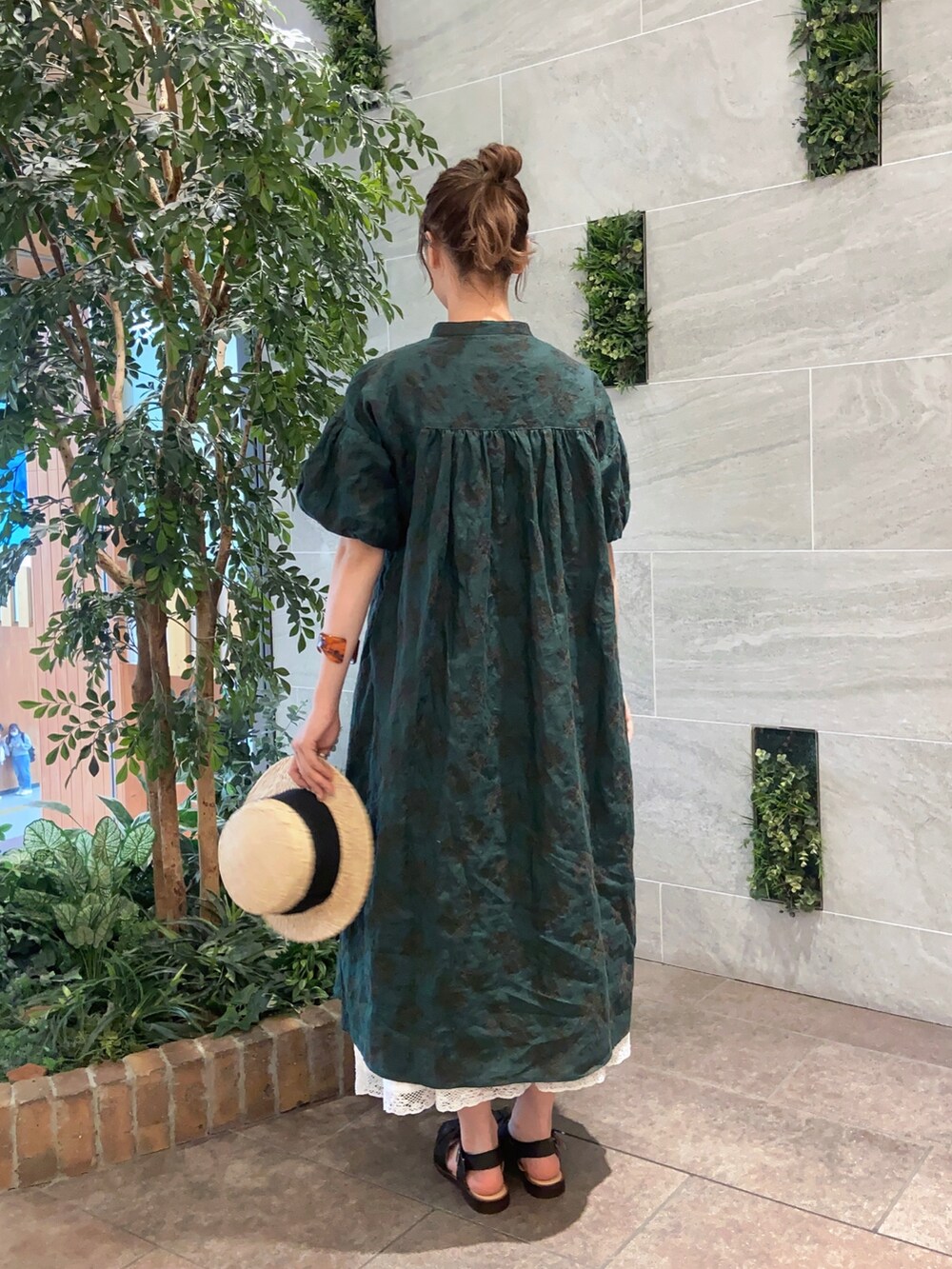 グリーン系のワンピース、ホワイト系のスカート、ブラック系のサンダルを着用したレディースの春コーディネートの2枚目の写真