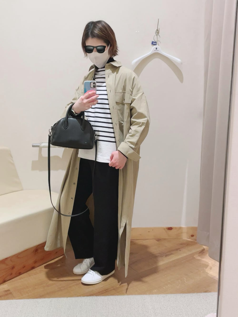 ブラック系のボストンバッグ、グリーン系のシャツワンピース、ホワイト系のスニーカーを着用したレディースの冬コーディネートの2枚目の写真